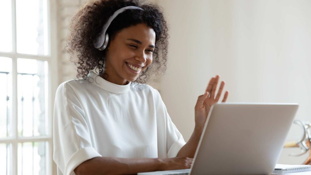 The image shows a smiling woman with curly hair wearing headphones and working on a laptop, representing the concept of "Virtual Assistant Services." The woman's positive and engaged demeanor suggests the potential benefits of leveraging virtual assistant services to enhance productivity and efficiency.