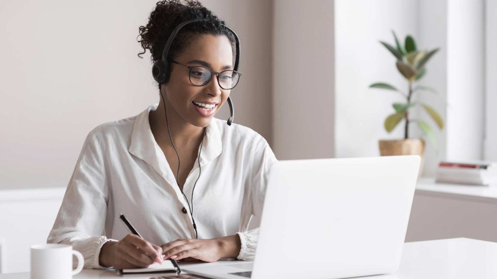 A woman wearing a headset while working on a laptop, suggesting a professional business environment where prospecting activities take place.