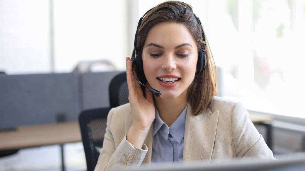 Customer Service Helpdesk - A woman in a professional business attire wearing a headset, projecting a friendly and helpful demeanor while assisting with customer inquiries."